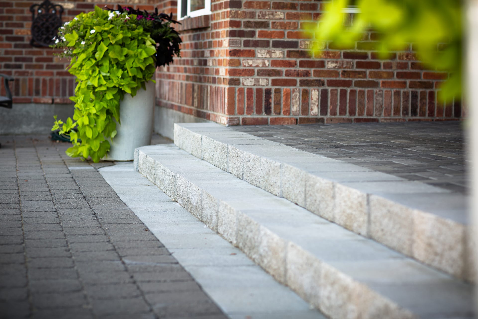 Paver steps set into a gentle slope connecting two patio levels