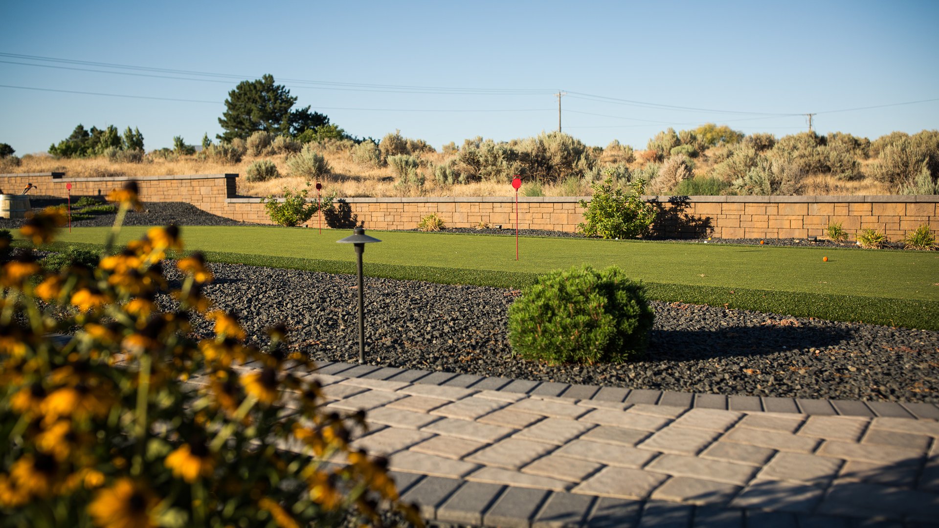 Synthetic putting green bordered by pavers and landscape lighting